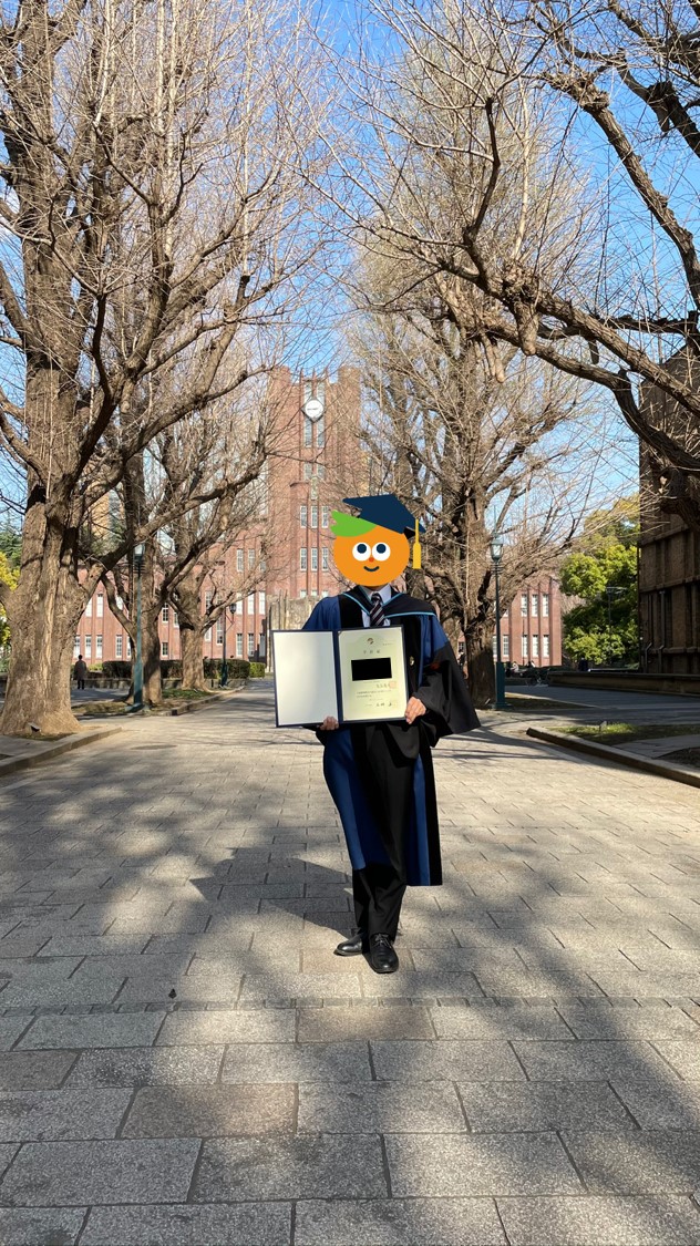 博士卒業時にガウンを着て学位記と一緒に写真